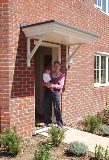 a person with their baby in the doorway of a red brick house
