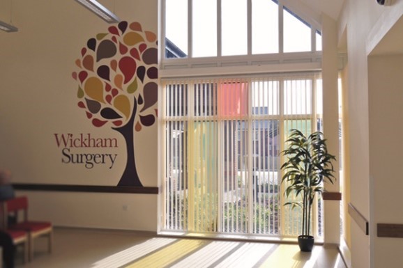 the inside of Wickham Surgery, which has a mural of a tree, a large window and a small plant to decorate